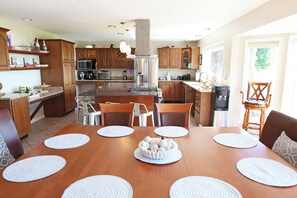 Une cuisine moderne avec des meubles en bois, un îlot central et un coin repas avec une table dressée pour quatre personnes.