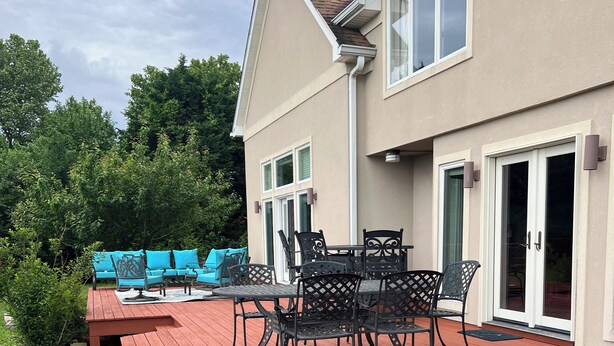 Eine Terrasse mit Gartenmöbeln und ein Haus mit beiger Fassade und großen Fenstern.