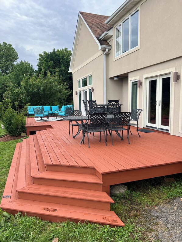 Eine Terrasse mit Gartenmöbeln und ein Haus mit beiger Fassade und großen Fenstern.