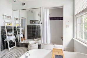 A bathroom with a bathtub, a shower, a mirror, and a window. - Looking Glass (Atlanta)