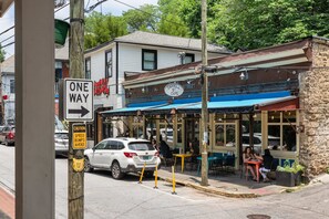 A street view with a cafe named 'CARROLL STREET CAFE' on the corner, a 'ONE WAY' sign, and a 'CAUTION SPEED BUMPS AHEAD' sign.