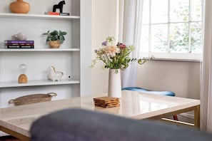 A room with a white table, a vase with flowers, and a bookshelf with books and decorative items. - Down the Rabbit Hole (Atlanta)