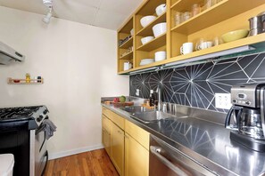 A modern kitchen with a gas stove, stainless steel sink, and a coffee maker.