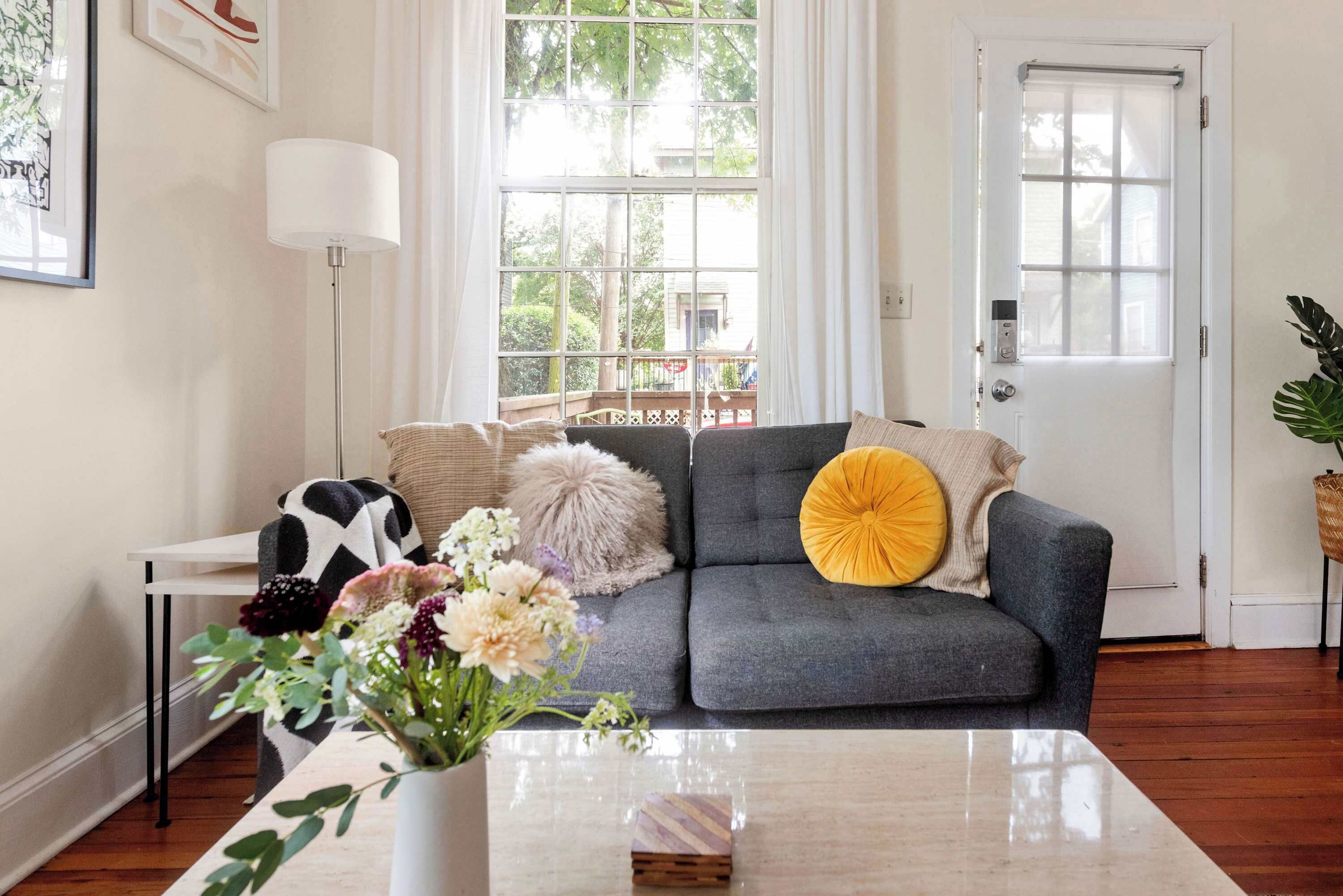 A living room with a grey sofa, a white coffee table, and a vase with flowers.