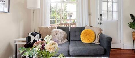 A living room with a grey sofa, a white coffee table, and a vase with flowers.