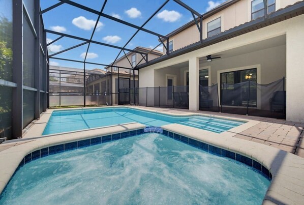A swimming pool with a glass enclosure, surrounded by a covered patio area.