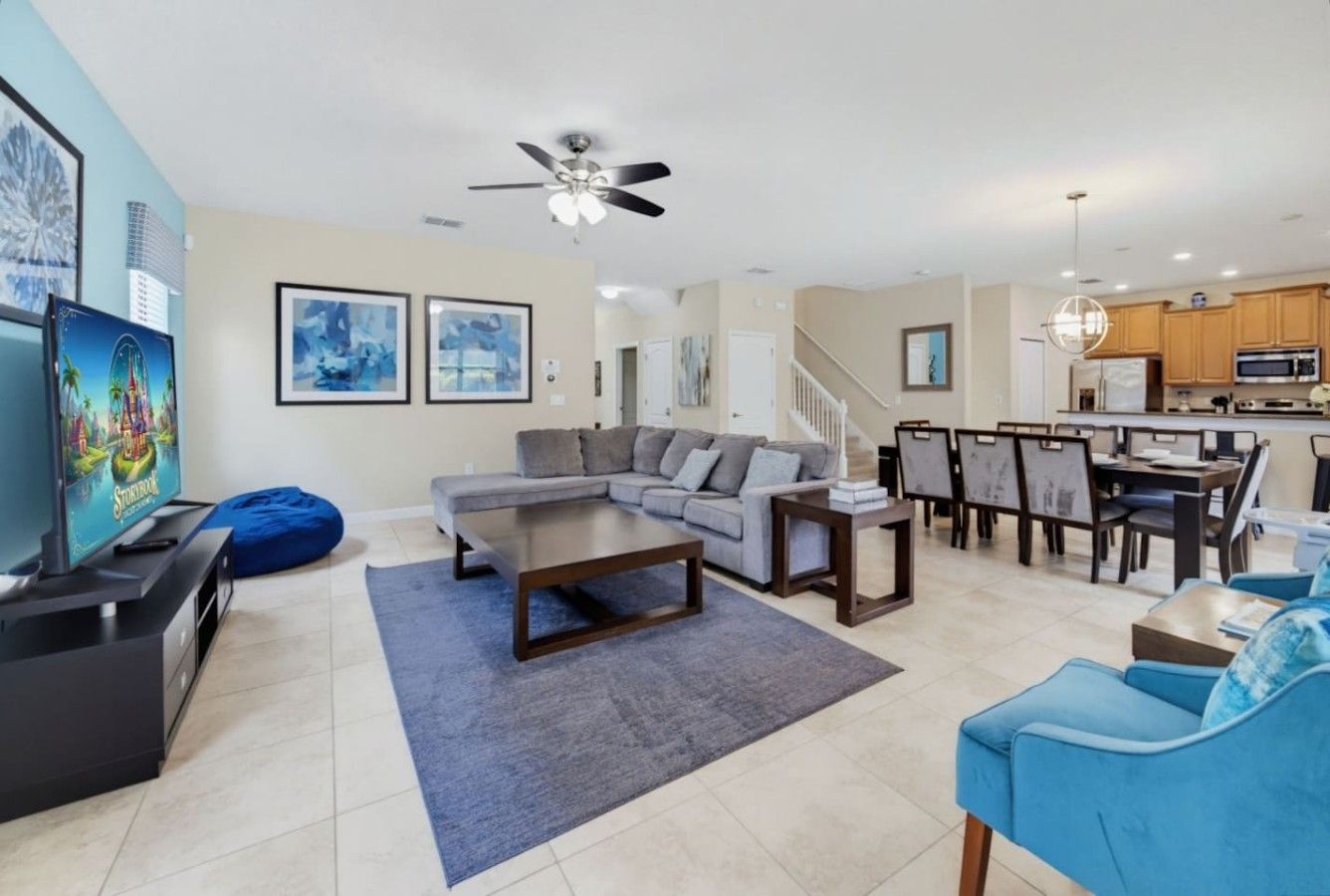 A modern living room with a sectional sofa, a coffee table, a TV, and a dining area with chairs and a table.