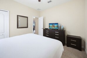 A bedroom with a large bed, a dresser, a television, and a door. - 6BR Family Friendly Resort Pool Home Near Disney (Davenport)