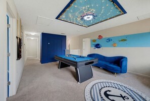 A room with a pool table, a blue couch, and a ceiling with a decorative light fixture. - 6BR Family Friendly Resort Pool Home Near Disney (Davenport)