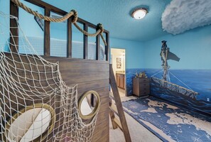 A room with a nautical theme, including a rope ladder, a ship's wheel, and a world map on the floor.