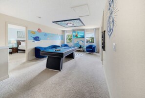 A room with a pool table, a sofa, and a television.