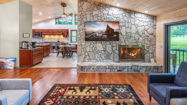 A spacious living area with a stone fireplace, a dining area, and a kitchen with wooden cabinets. - Private Mountain Home, 2miles To Ski, Hot Tub, Views, Fireplace, & Pet Friendly! (Beech Mountain)