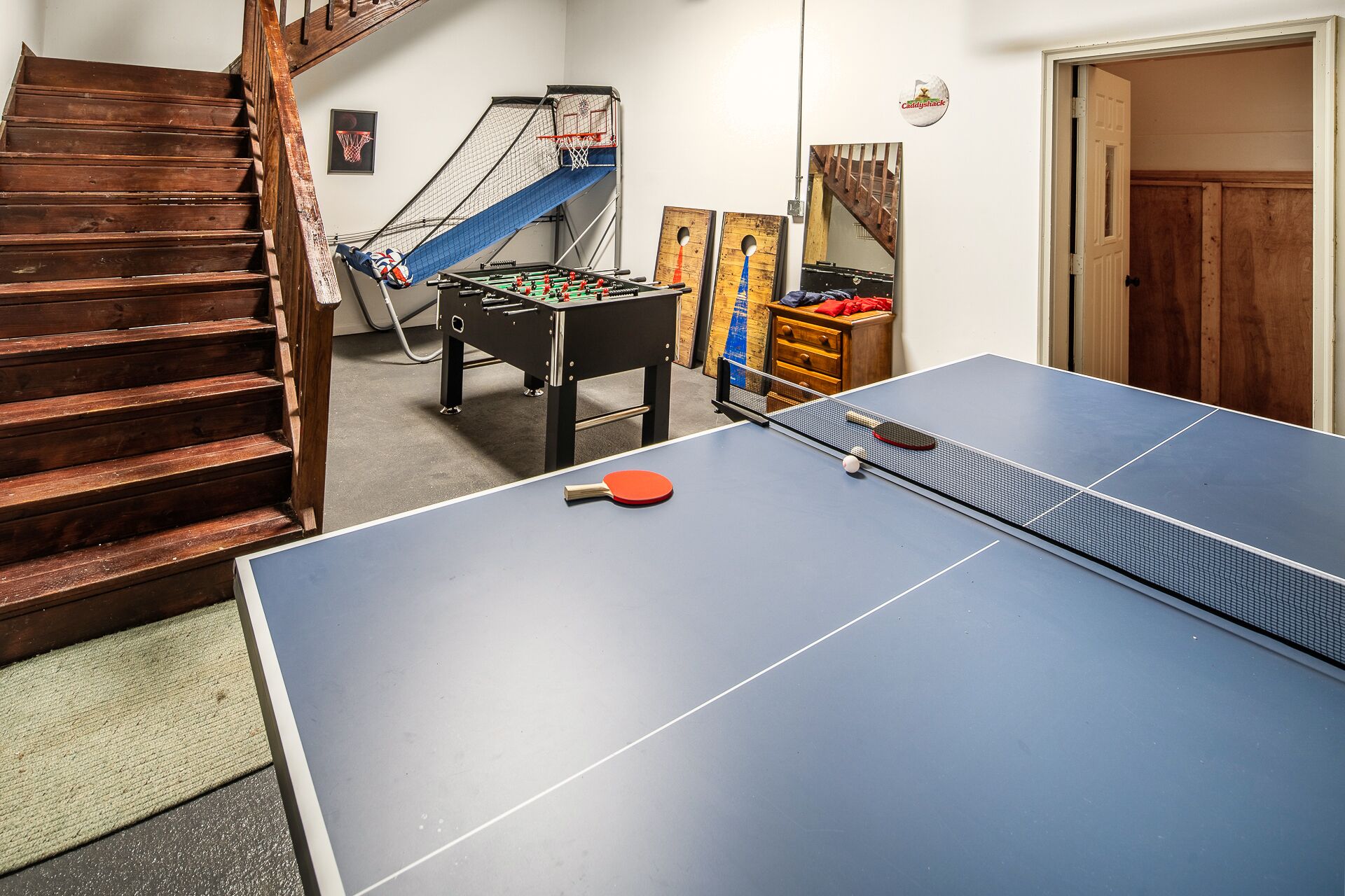 Une pièce équipée d’une table de ping-pong, d’un baby-foot et d’un escalier.