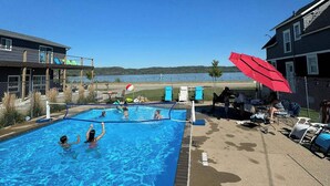 A swimming pool with a volleyball net, lounge chairs, and a red umbrella. - Double Queen Room Sum (Lake City)