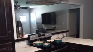 A kitchen with dark wooden cabinets, a stainless steel stove, and teal-colored pots. - Charming Home Comfy Beds Private Backyard with Fire Pit  (Hattiesburg)