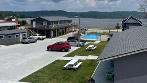 A parking lot with several cars, a swimming pool, and a grassy area with picnic tables. - Single Queen Room w/ Sleeper Sofa (main level) (Lake City)