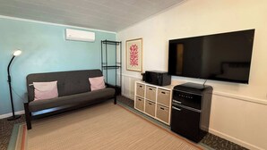 A living room with a sofa, a flat-screen TV, a coffee maker, and a refrigerator. - Single Queen Room w/ Sleeper Sofa (main level) (Lake City)