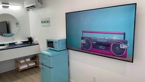 Een moderne badkamer met een wastafel, spiegel en een aan de muur bevestigde televisie waarop een klassieke auto te zien is.