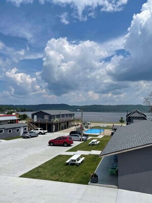 A parking area with several cars, a swimming pool, and a building with a sloped roof. - Poolside Double Queen Room (main level) (Lake City)