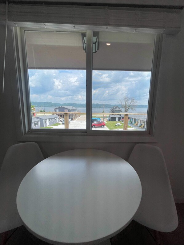 A room with a large window, a round table, and two chairs. - Single King Room (Upper Level) (Lake City)