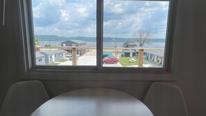 A room with a large window, a round table, and two chairs. - Single King Room (Upper Level) (Lake City)