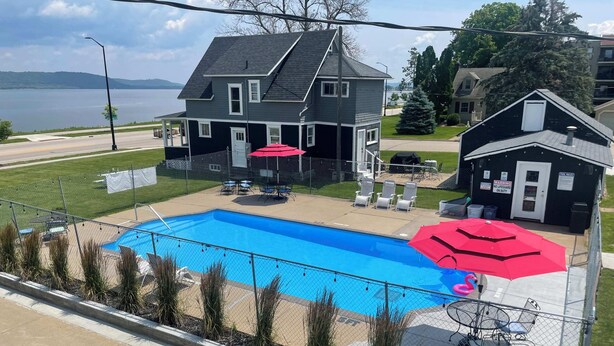 A residential property with a swimming pool, a fenced patio area with outdoor furniture, and a house with a dark exterior. - Single King Room (Upper Level) (Lake City)
