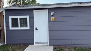 A single-story house with a white door, a small window with a grid pattern, and a mailbox with the number 4 on it.