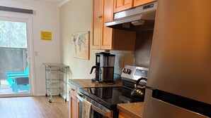 Une cuisine avec des meubles de rangement en bois, un réfrigérateur en acier inoxydable, une cuisinière et une machine à café.