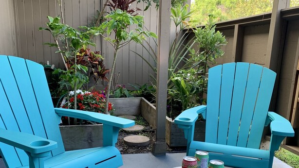 Un espace patio avec deux fauteuils Adirondack turquoise, une petite table ronde et une boîte d’Alka-Seltzer posée sur la table.