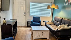 Un salon avec un canapé, une table basse, un téléviseur et une porte.