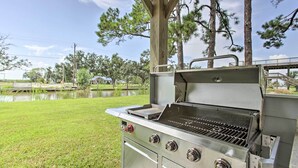 Una parrilla exterior con rejilla metálica, panel de control con perillas y acabado de acero inoxidable.
