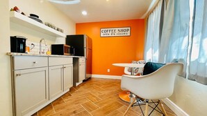 A compact kitchen with white cabinets and a coffee shop sign on the wall. - Bell Haus-Private Hot Tub, 1/1, 100 yds to Main St (Fredericksburg)