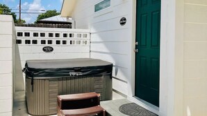A hot tub and a chair outside a building with a green door and a sign that reads "Bell Haus." - Bell Haus-Private Hot Tub, 1/1, 100 yds to Main St (Fredericksburg)