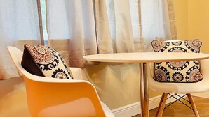 A room with a round white table and two white chairs with patterned cushions. - Bell Haus-Private Hot Tub, 1/1, 100 yds to Main St (Fredericksburg)