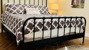 A bed with a patterned bedspread and pillows, a black metal frame, a bedside lamp, and a framed picture on the wall. - Bell Haus-Private Hot Tub, 1/1, 100 yds to Main St (Fredericksburg)