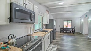 A modern kitchen with stainless steel appliances, a wooden countertop, and a dining area with a table and chairs. - 2 Mi to Rainbow Lake: Woodsy Retreat w/ Deck! (Lakeside)