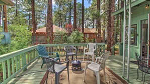 A wooden deck with outdoor furniture, surrounded by tall trees. - 2 Mi to Rainbow Lake: Woodsy Retreat w/ Deck! (Lakeside)