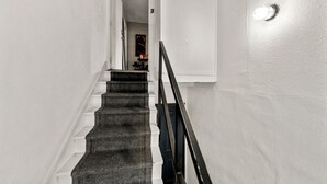 A staircase with a black railing leading to a landing, white walls, and a door with the number 3.