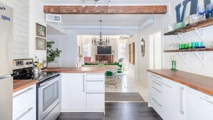 A modern kitchen with white cabinetry, a wooden countertop, and a central island.
