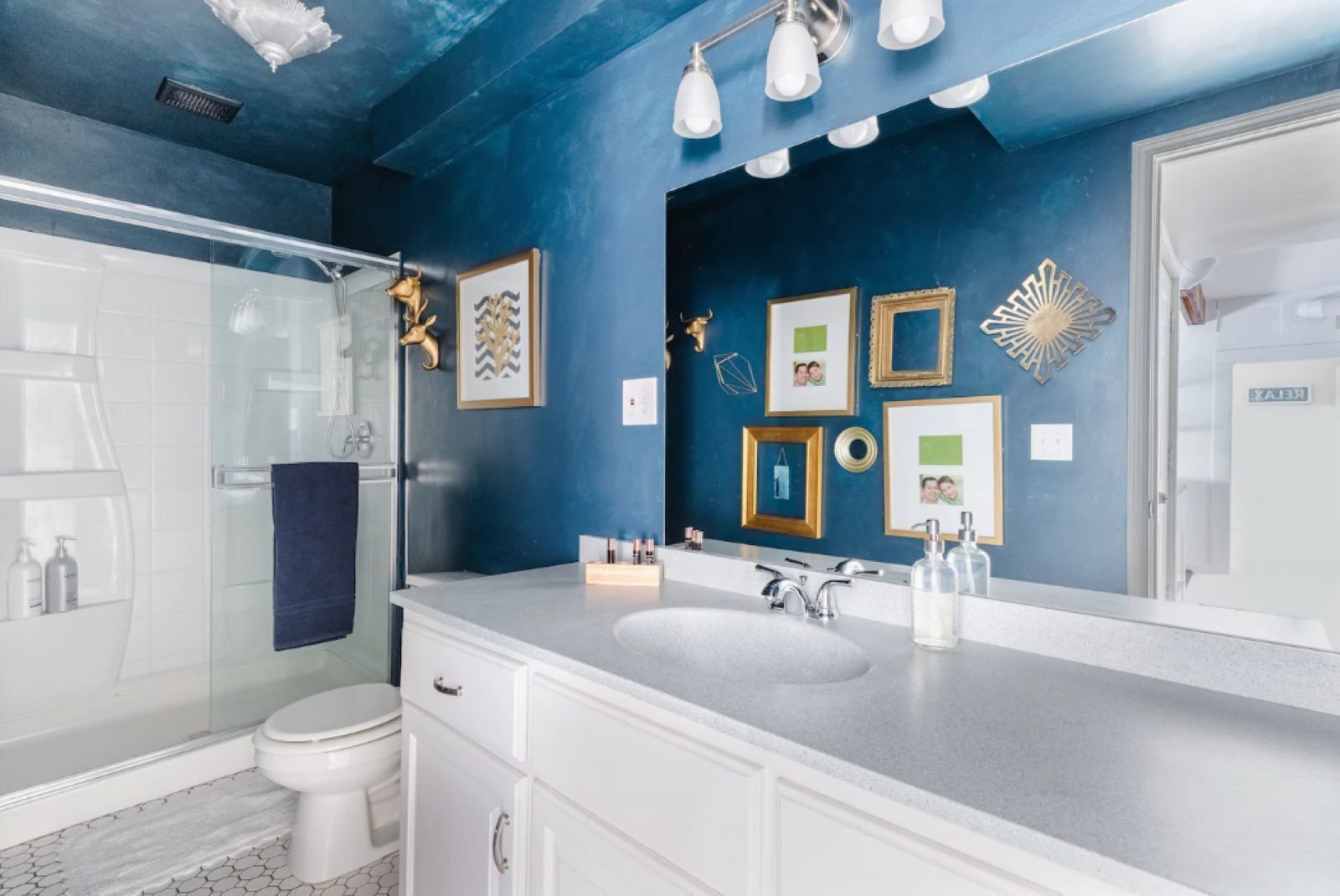 A modern bathroom with a large mirror, a white sink, and a glass shower enclosure.