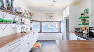 A modern kitchen with white cabinets, a wooden countertop, and a 'LOVE' sign on the wall.