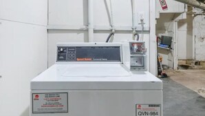 A commercial washer with a control panel, a label with contact information, and a barcode.