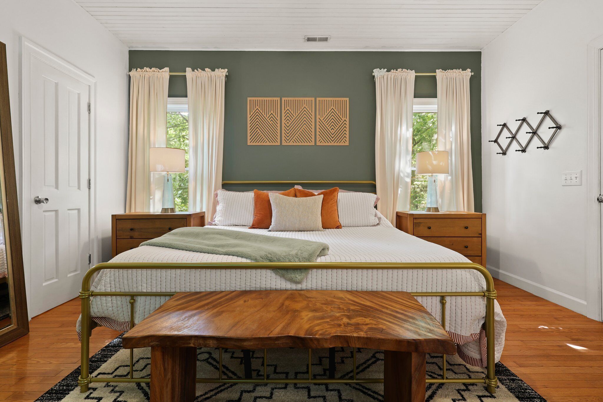Une chambre à coucher comprenant un lit, des tables de chevet, un banc et un mur orné de panneaux décoratifs.