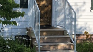 A house with a wooden front door, white railings, and a striped awning. - Charming suite with private entrance (Dallas)