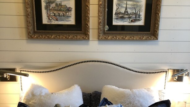 A bed with a white headboard, multiple pillows, and two framed pictures on the wall above. - Charming suite with private entrance (Dallas)