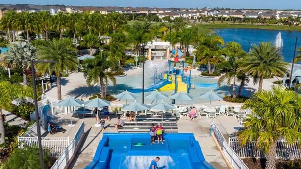 A water park with a large pool, slides, and palm trees. - NEW Lake View Villa Near Disney w/ Pool & Spa! (Four Corners)