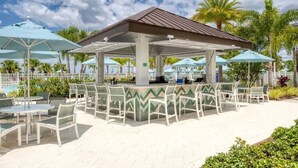 An outdoor patio area with white chairs and tables, a covered seating area, and a pool in the background. - NEW Lake View Villa Near Disney w/ Pool & Spa! (Four Corners)