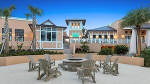 A patio area with Adirondack chairs and a fire pit, surrounded by palm trees and a building with a sign reading "5th Floor". - NEW Lake View Villa Near Disney w/ Pool & Spa! (Four Corners)