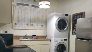 Eine kleine Küche mit Waschmaschine, Kühlschrank und einer Pendelleuchte.