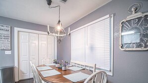 Ein Esszimmer mit einem Holztisch, weißen Stühlen, einer Kristallleuchtre und einer Wanduhr.
